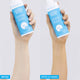 Two hands holding bottles of MooGoo tanning water with 'Before' and 'After 24 Hours' text on a white background.