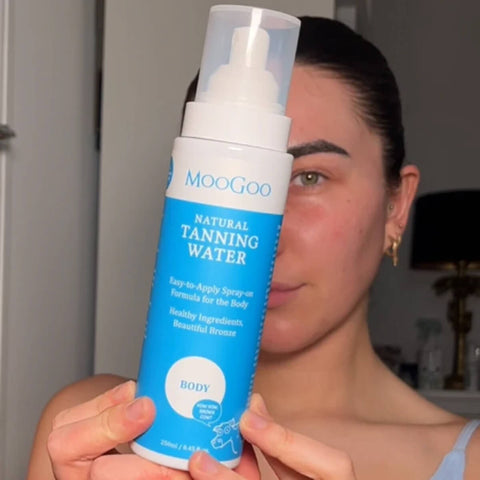 Person holding a bottle of MooGoo Natural Tanning Water.