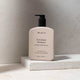 Mukti Botanique Shampoo bottle on a marble surface with a neutral background
