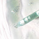 Close-up of dropper applicator filled with hyaluronic marine serum on a surface with more serum spread around.