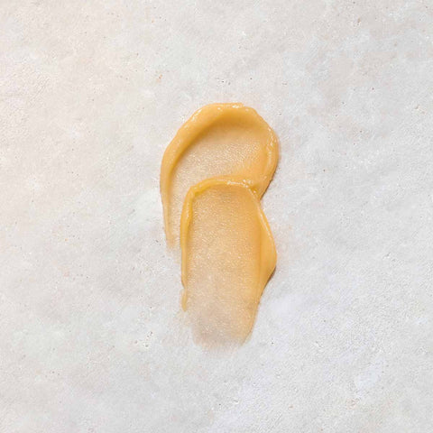 Swatch of whipped honey and macadamia lip balm on a stone background.