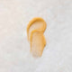 Swatch of whipped honey and macadamia lip balm on a stone background.