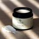 Nada Organics Golden Trio Tallow Balm jar on a textured surface with a light background.