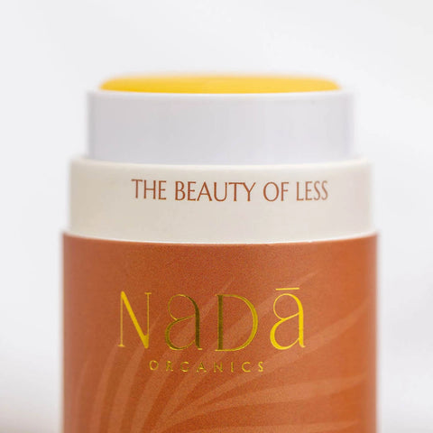 Nada Organics tallow balm with lid off showing yellow balm with gold text on a white background