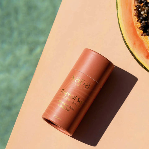 Nada Tropical Sol with papaya on a peach-coloured surface with a blurred green background.