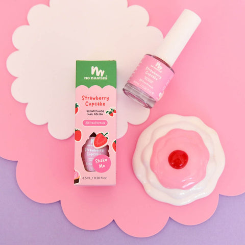 Nail polish styled on a pink, white and purple background with a toy cupcake. 