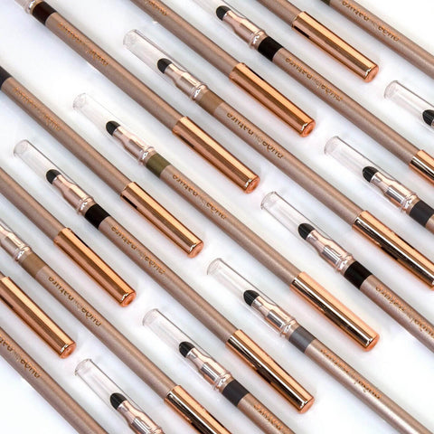 Set of rose gold eye pencils on a white background.