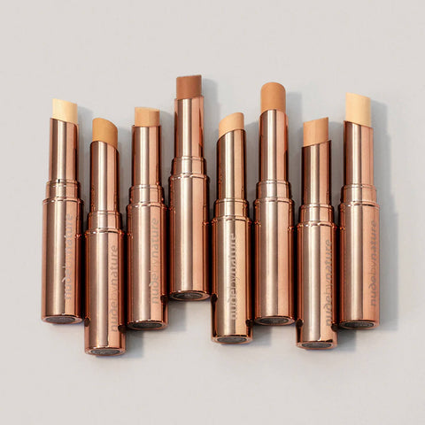 Set of concealer sticks with Nude by Nature logo on a light grey background.