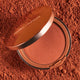Compact Nude By Nature Pressed Matte Mineral Bronzer 10g on a red powder background.