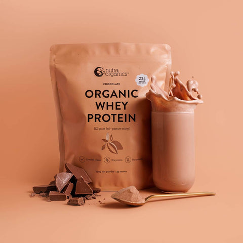 Nutra Organics Organic Whey Protein - Chocolate 750g package with a cup of chocolate protein shake on a peach background.