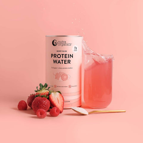 Nuta Organics Protein Water - Berry Bliss 450g can with a glass of pink water, strawberries, and raspberries on a pink background.