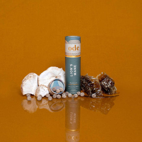 Ode Lion's Mane mushroom supplement tube on an orange background with mushrooms & honeycomb.