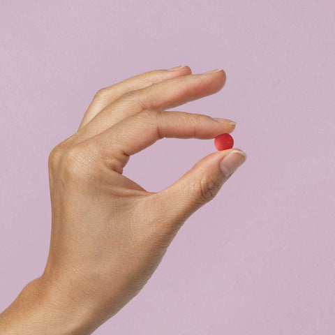 Light purple background with a hand holding a red iron tablet.