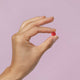 Light purple background with a hand holding a red iron tablet.