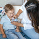 Woman applying essential oil blend to a child's chest on a couch.