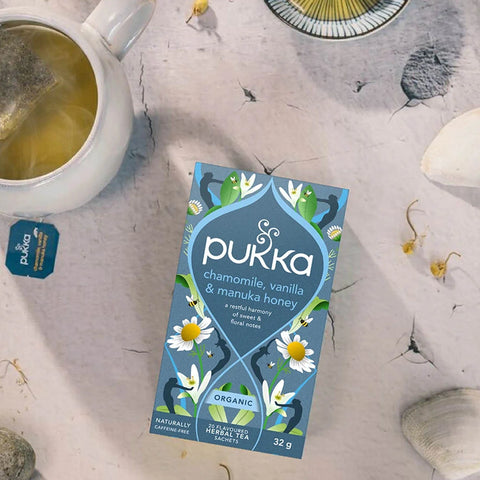 Pukka tea box with a cup of tea and teabag on a textured surface