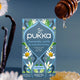 Pukka chamomile, vanilla & manuka honey tea package with honey drizzle and vanilla beans.