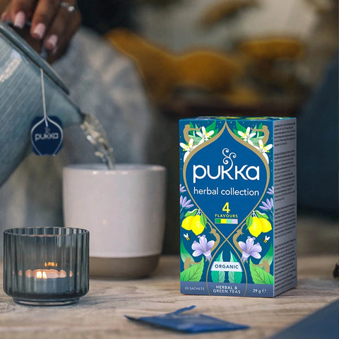 Pukka herbal collection tea packaging on a table with a blurred background