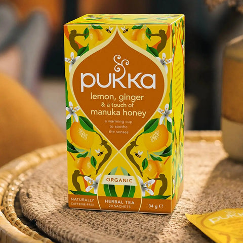 Pukka lemon, ginger, and manuka honey tea box on a woven surface