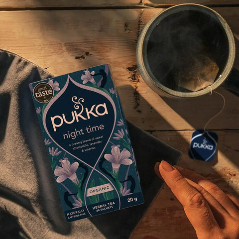 Pukka Herbs Night Time tea box next to a brewing cup of night time tea.