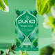 Pukka three mint herbal tea packaging with green leaves in the background