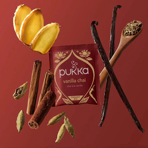 Pukka vanilla chai packaging with vanilla beans, cinnamon sticks, and cardamom on a red background