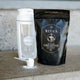 Ritua creatine supplement packaging with a shaker and scoop on a neutral background.