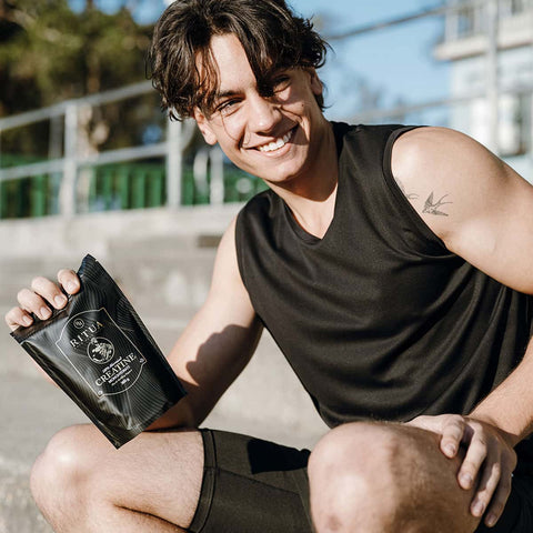Person holding a black creatine bag outdoors.