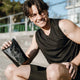 Person holding a black creatine bag outdoors.