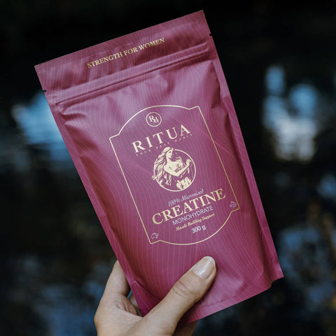 Purple package of Ritua Creatine Monohydrate held by a hand against a blurred background.