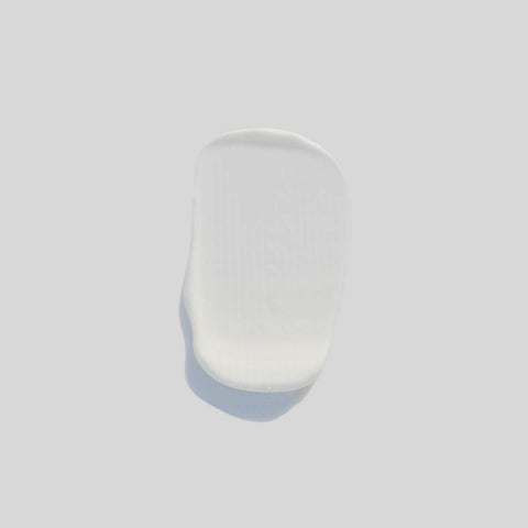 Creamy swatch of balancing face & neck moisturiser on a grey background. 