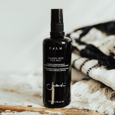 Sodashi calming face mist styled on a wooden surface with a patterned black and white throw.