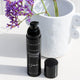 Eye lifting gel with the cap off, positioned in front of a white pot with purple flowers.