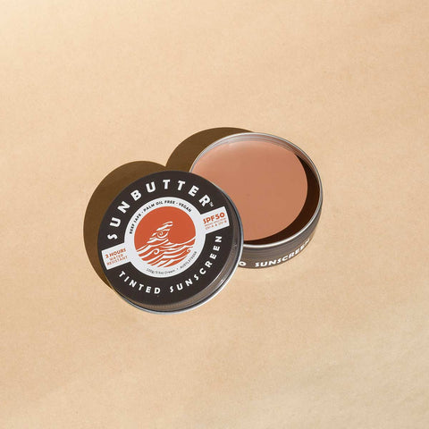 Sunbutter tinted sunscreen tin on a beige background