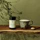 Supplement bottle labeled 'Cordyceps' on a wooden surface with a mug and plant in the background.
