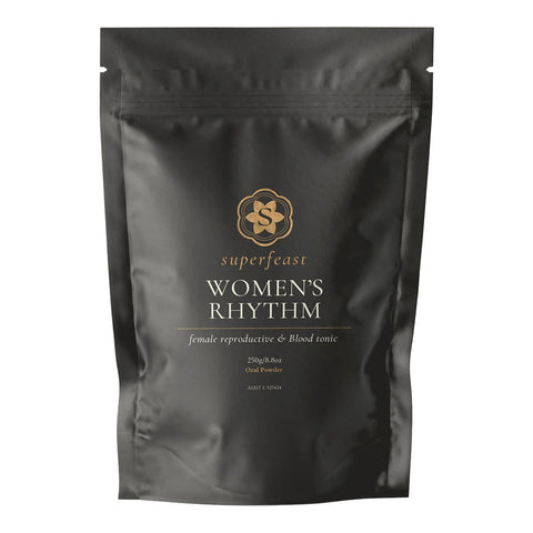 A black resealable stand-up pouch of Superfeast Women's Rhythm food powder, featuring gold and white text on a clean white background.