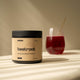 Container labeled 'switch beetroot' on a surface with a glass of red liquid in the background.