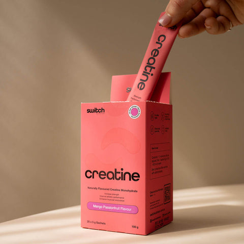 Pink creatine supplement packaging with a hand holding a sachet against a beige background.
