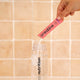 Person pouring creatine from pink sachet into a clear drink bottle.