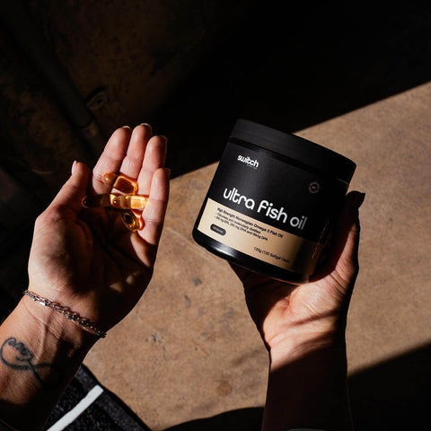 Person holding a container of ultra Fish oil and fish oil capsules.