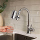 Person filling a glass with water from a kitchen faucet with a water filter attachment.