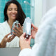 Woman holding Tappwater ShowerPro Diamond Filter. Removes impurities from water to protect skin and hair.