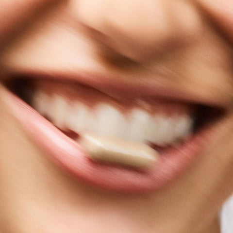 Close-up of a person's mouth with Debloat Biotic capsule from The Beauty Chef.