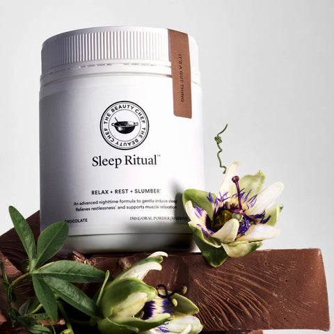 Sleep Ritual product from The Beauty Chef with flowers and chocolate on a light gray background.