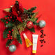 Christmas-themed arrangement with decorative elements and skincare products on a red background.