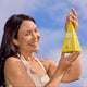 Woman holding a yellow product against a blue sky.