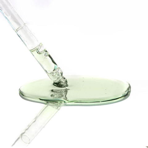 Glass dropper with green liquid on a white background