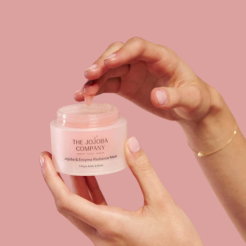 Hand holding The Jojoba Company Jojoba & Enzyme Radiance Mask product.