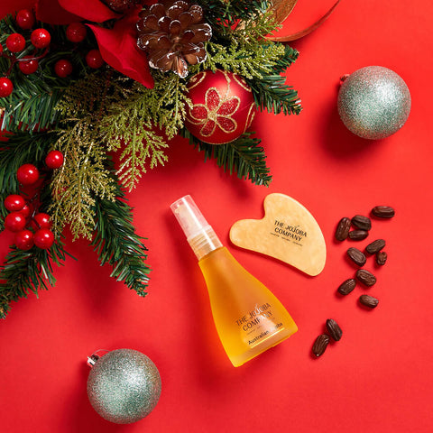 Cosmetic bottle with wooden tool and Christmas decorations on a red background.