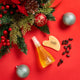 Cosmetic bottle with wooden tool and Christmas decorations on a red background.